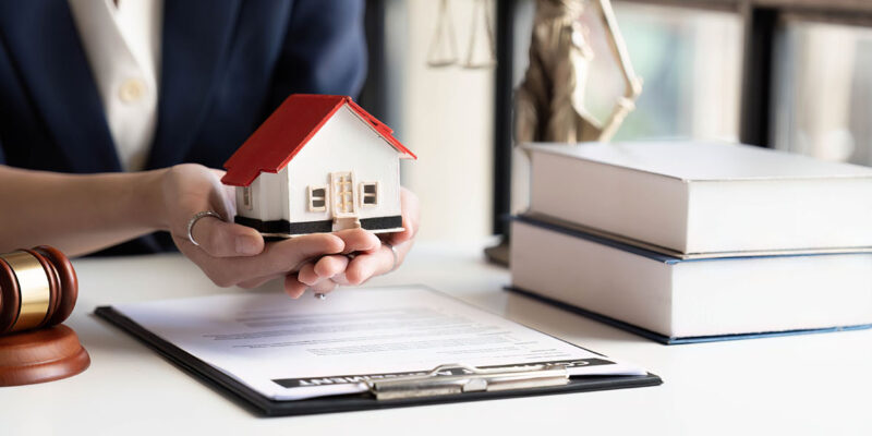 Divorce lawyer holding toy house above mortgage and gavel